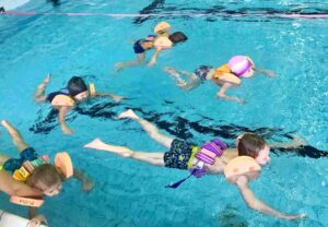 Plavající děti v bazénu.